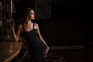 Elegante Frau im schwarzen Kleid an einer Bar in Düsseldorf